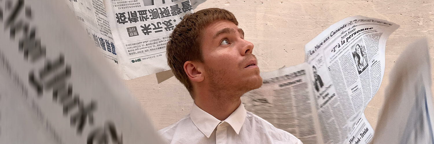 A young white man in a white shirt looking up and sideway, surrounded by flying newspaper pages