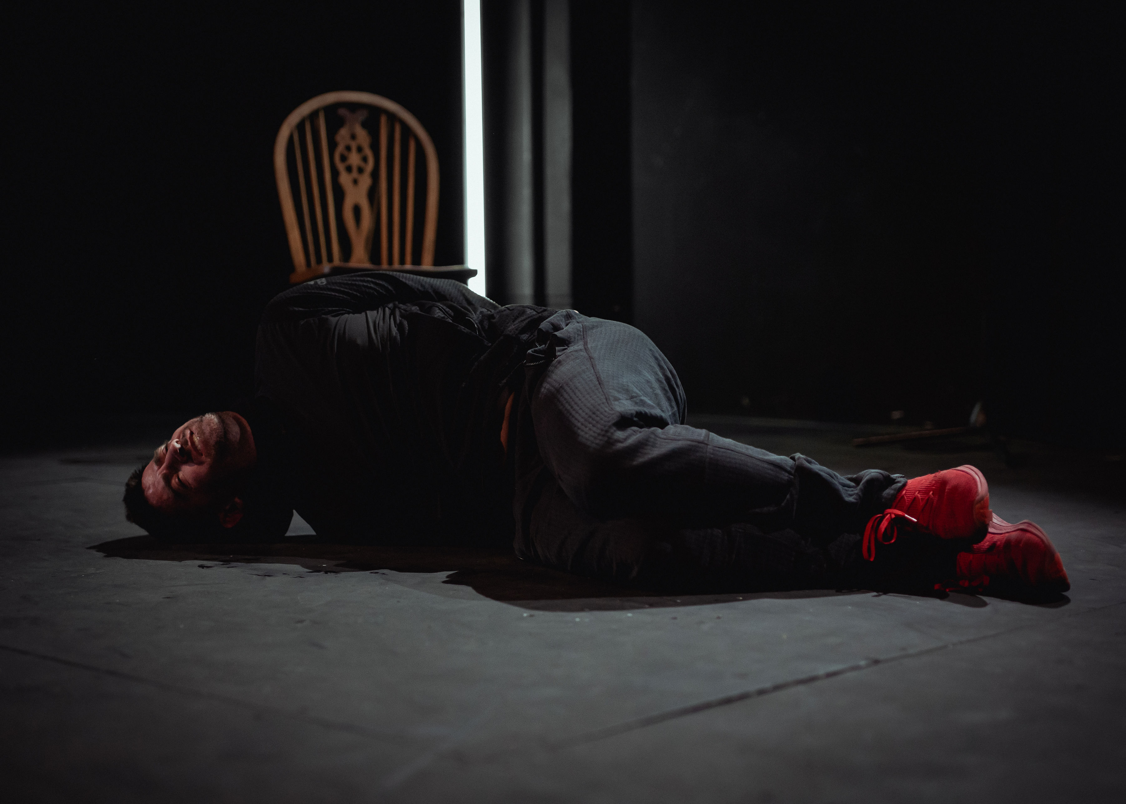 A caucasian man lying on the floor with hi s arms and legs tied