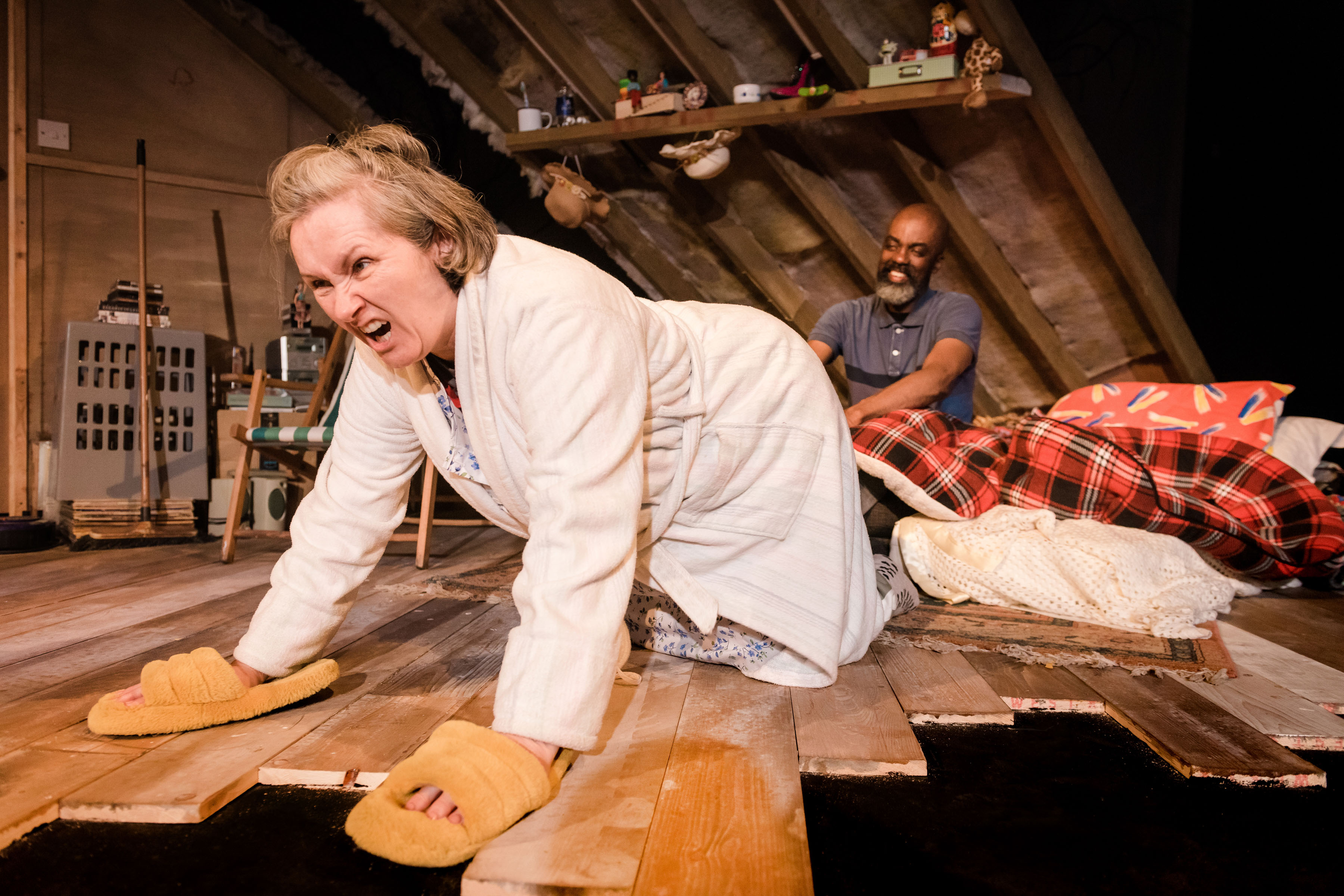 A middle aged white woman looking angrily on all fours on the floor of an attic