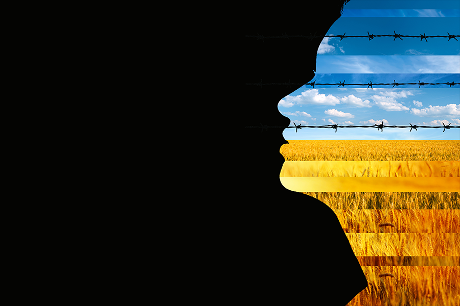 A silhoutte of a woman's face in profile on a black background. The silhoutted image shows a wheat field surrounded by barbed wire