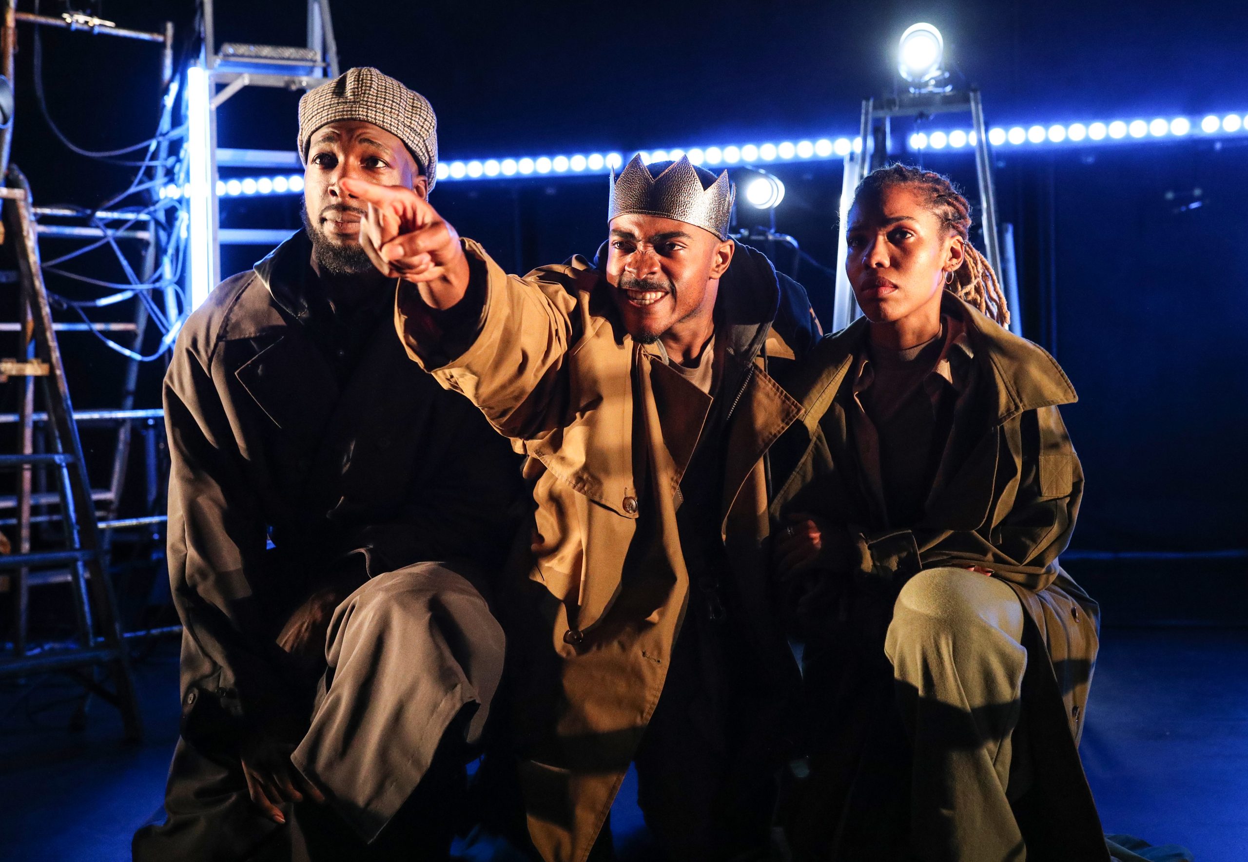 Three black actors on stage in Richard the Second at Omnibus Theatre. They are looking up and the centre performer is wearing a crown and pointing.