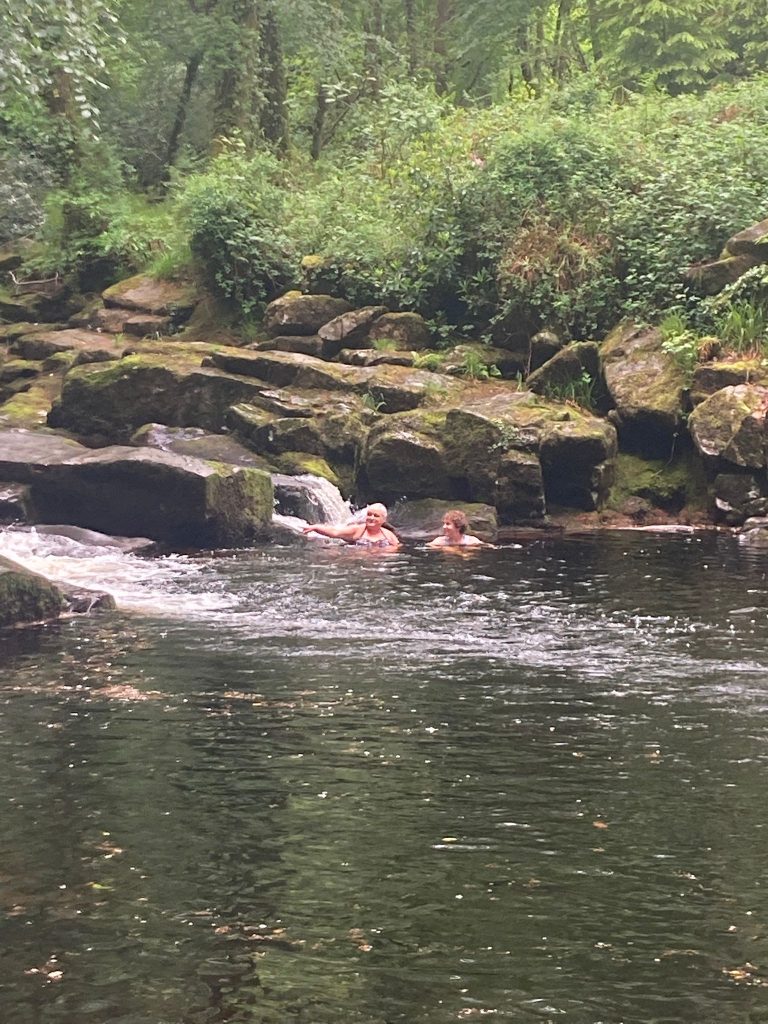 A photo of two people swimming in an outdoor lake/river