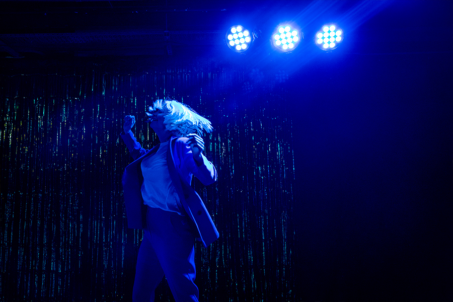 A woman dances on stage the lights are electric blue.
