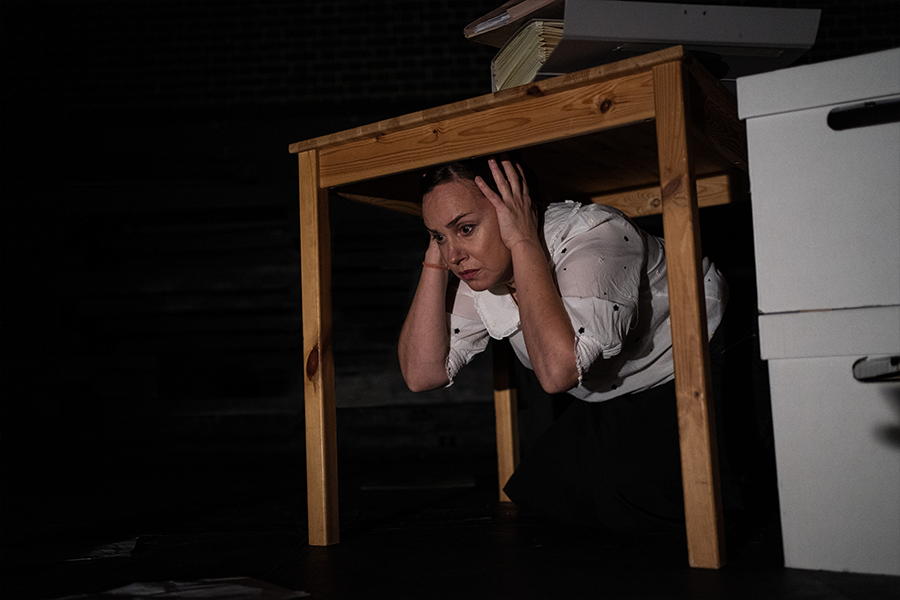 A woman covering her ears underneath a wooden table