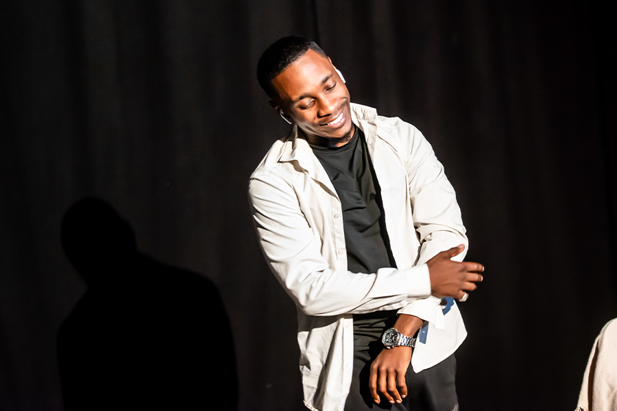 A black man smiles looking towards the floor as he performs