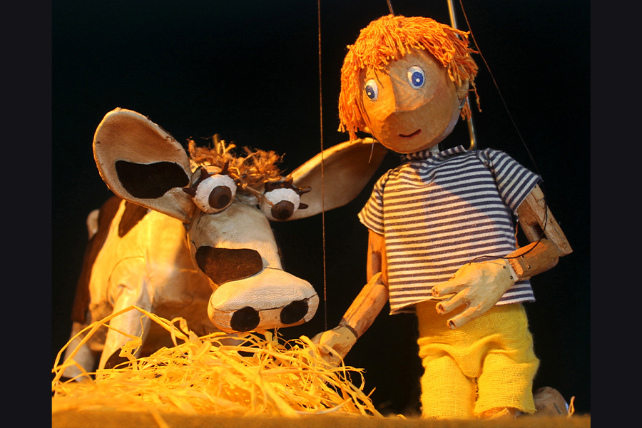 The puppet cow is eating hay next to jack the puppet