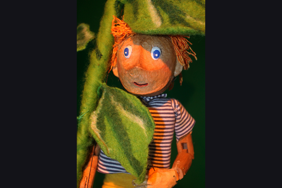 Puppet jack looks with his blue eyes between the leaves