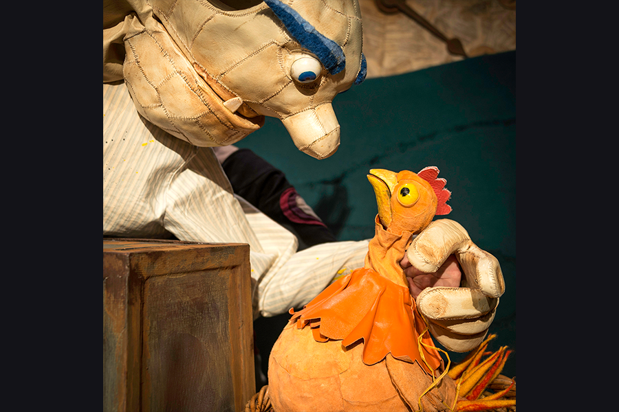 The puppet giant looks angry grabbing the bewildered chicken who is looking up at him