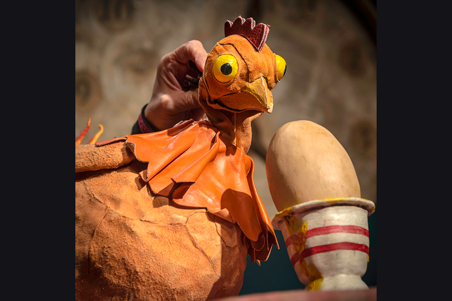 A puppet chicken stares at an egg in an egg cup