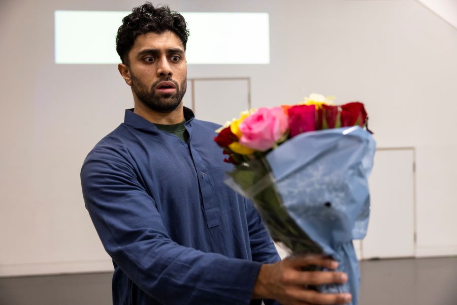 A man holds a bouquet of roses in front of him. He looks worried.